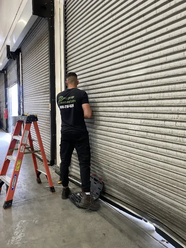 PLL Garage Doors and Gates technician repairing a commercial roll-up door