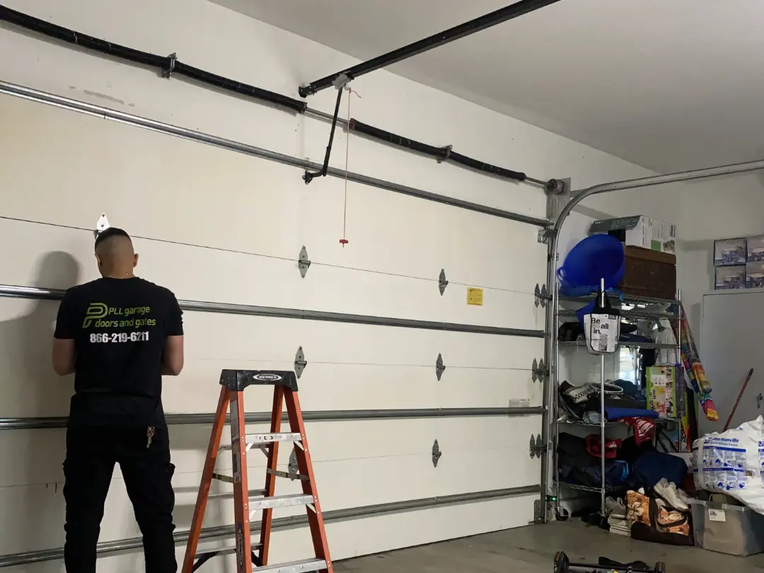 Uniformed PLL technician repairing a residential garage door