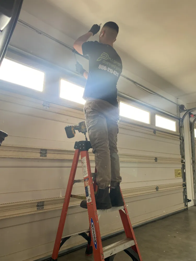 PLL technician on a ladder working on a residential garage door