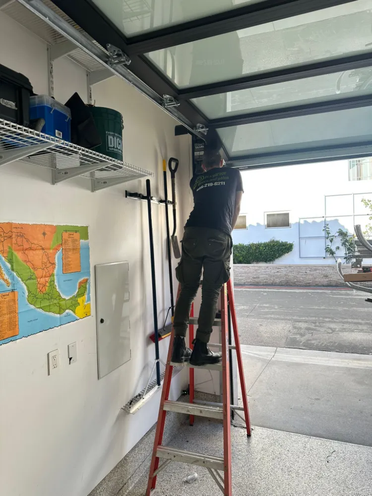 PLL technician on a ladder servicing a glass panel garage door