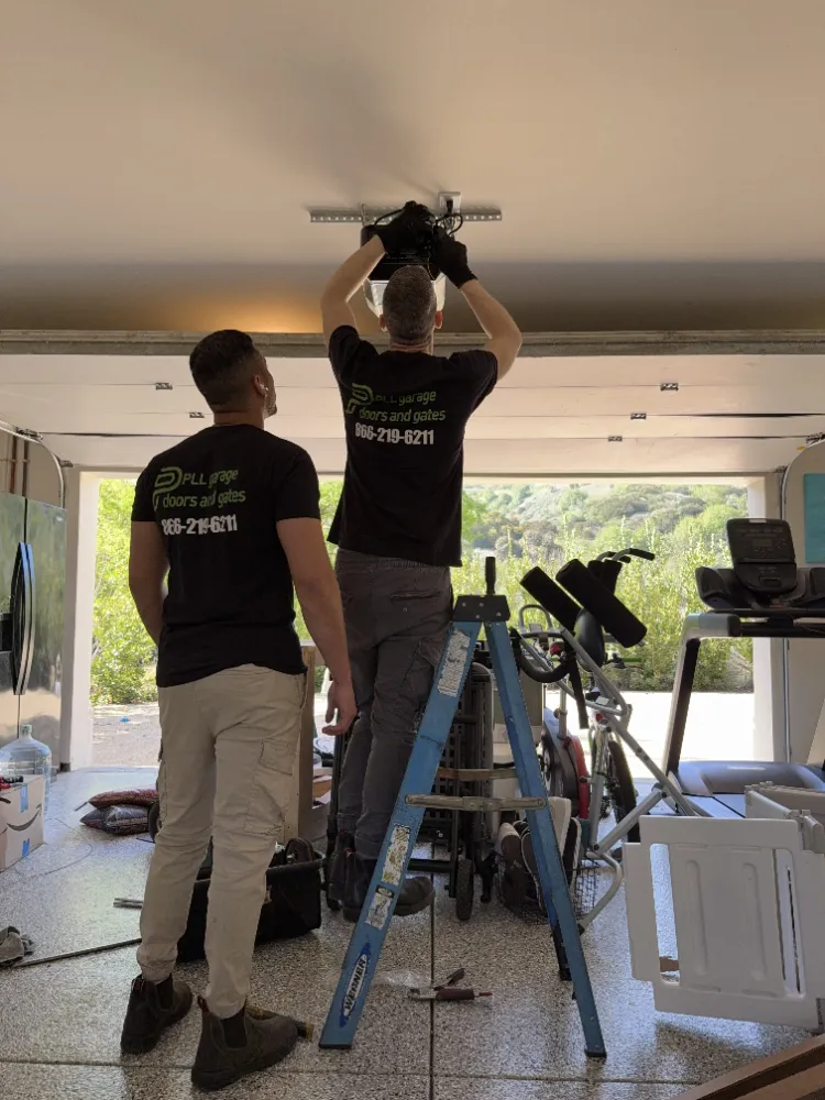Two PLL technicians mounting a garage door opener to the garage ceiling